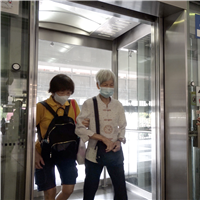 SMRT station staff holds the elevator door for an elderly passenger