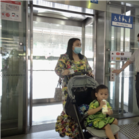 SMRT station staff holds the elevator door for a commuter with a pram